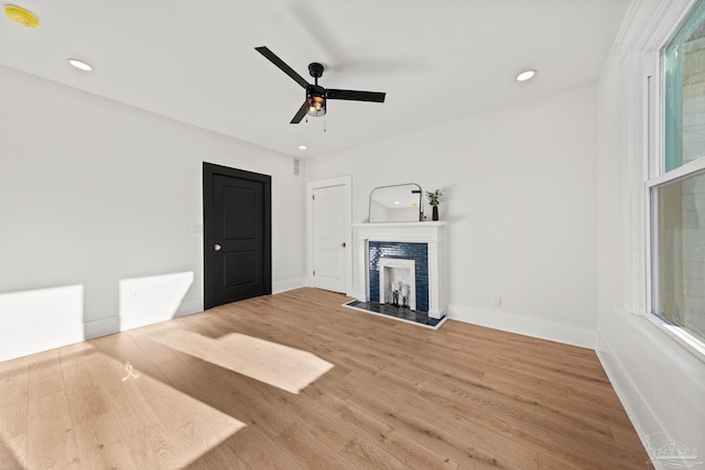 unfurnished living room featuring a ceiling fan, wood finished floors, recessed lighting, baseboards, and a tile fireplace