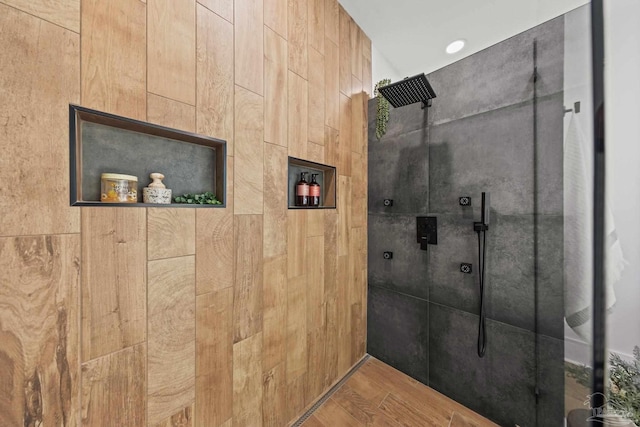 bathroom with wood finished floors and a tile shower