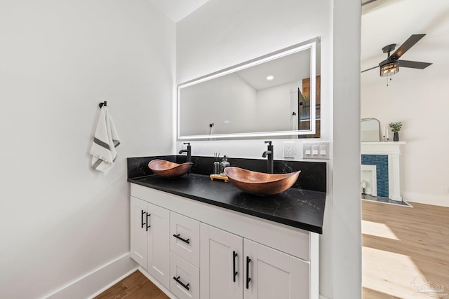 bathroom featuring double vanity, wood finished floors, ceiling fan, and a sink