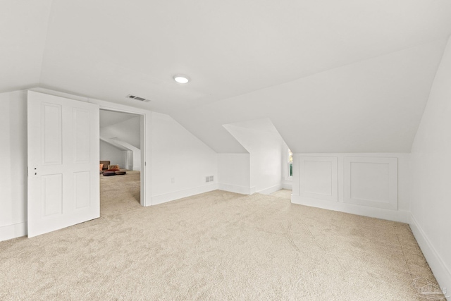 additional living space with lofted ceiling, carpet flooring, and visible vents