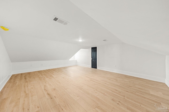 additional living space featuring visible vents, baseboards, lofted ceiling, and light wood-style floors