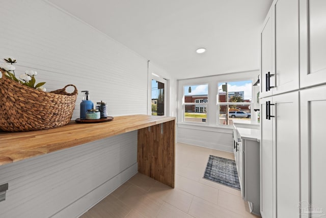 interior space featuring white cabinetry, light tile patterned flooring, and butcher block counters