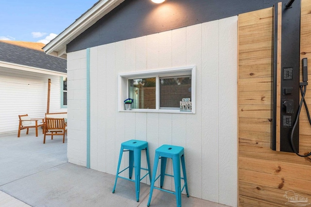 entrance to property featuring a shingled roof and concrete block siding