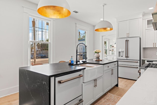 kitchen featuring visible vents, high end fridge, light wood-style flooring, and a sink