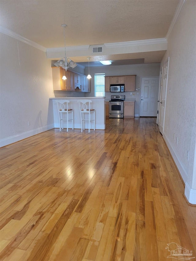 kitchen featuring visible vents, light wood-style flooring, appliances with stainless steel finishes, a peninsula, and a kitchen breakfast bar