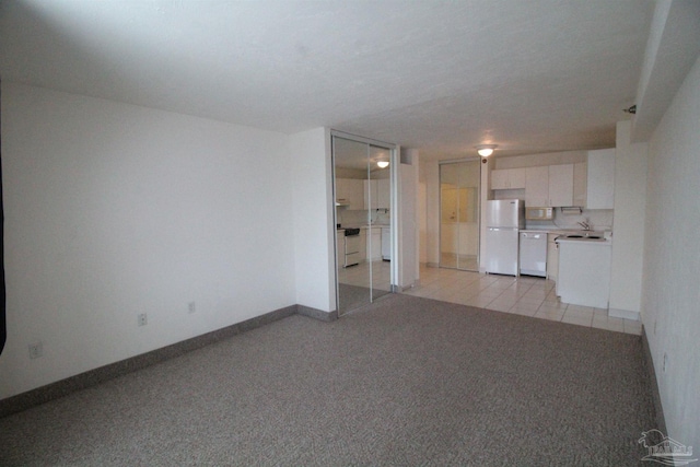 unfurnished living room featuring sink and light tile patterned floors