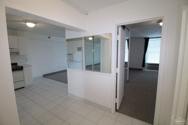 interior space featuring stove, white fridge, white cabinets, and light colored carpet