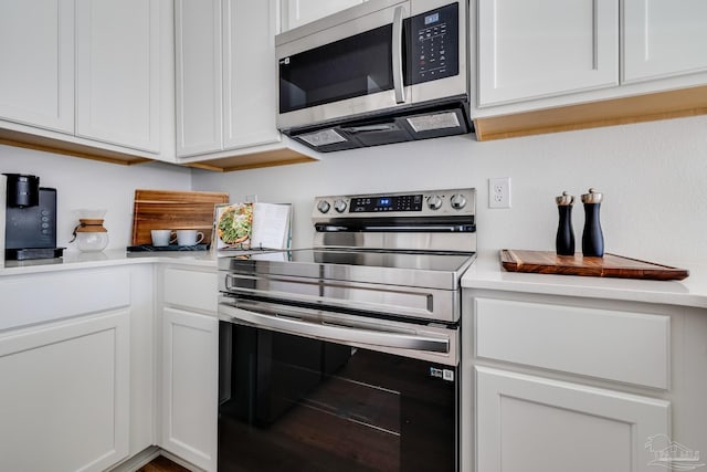 kitchen featuring stainless steel appliances, light countertops, and white cabinets