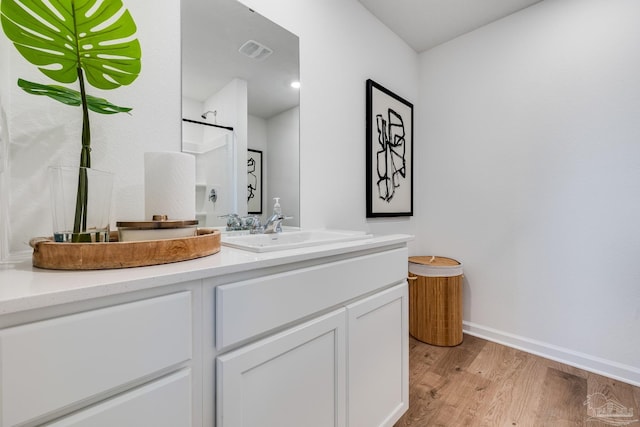 bathroom with wood finished floors, baseboards, vanity, and a shower