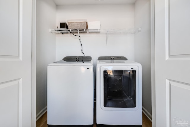 clothes washing area featuring washer and clothes dryer, dark wood-style flooring, and baseboards