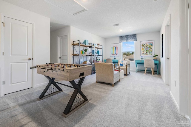 recreation room with carpet flooring, a textured ceiling, attic access, and baseboards