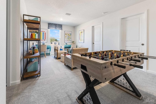 playroom featuring light carpet, a textured ceiling, and baseboards