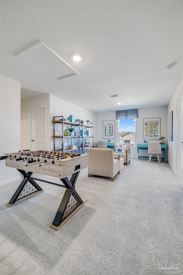 playroom featuring a textured ceiling, carpet flooring, attic access, and baseboards