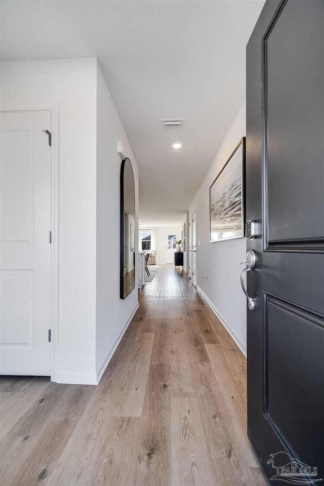 hallway with light wood-style flooring and baseboards