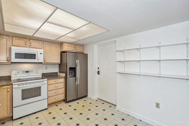 kitchen featuring dark countertops, white appliances, light floors, and light brown cabinetry