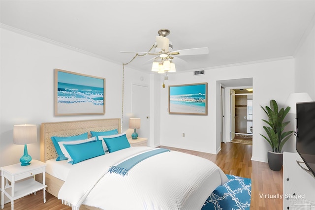 bedroom featuring crown molding, visible vents, a ceiling fan, wood finished floors, and baseboards