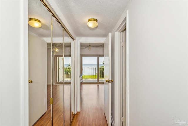 hall with a textured ceiling and hardwood / wood-style flooring