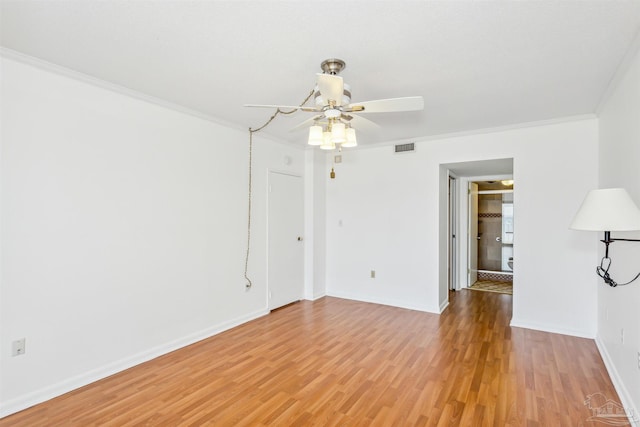 spare room with ceiling fan, light wood-style flooring, visible vents, baseboards, and ornamental molding