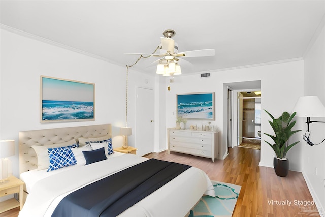 bedroom featuring baseboards, visible vents, crown molding, and wood finished floors