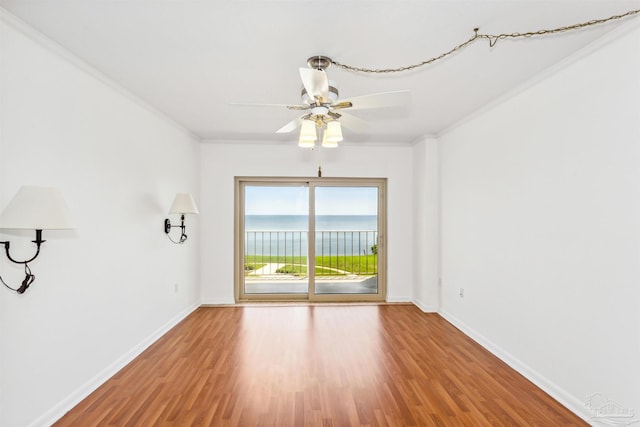 spare room with ornamental molding, a ceiling fan, baseboards, and wood finished floors