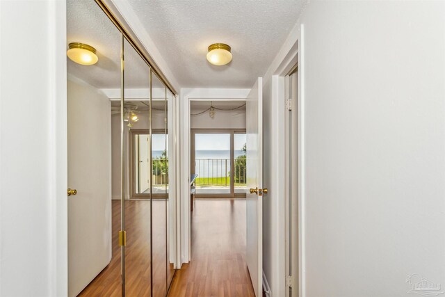 hallway with a textured ceiling and wood finished floors