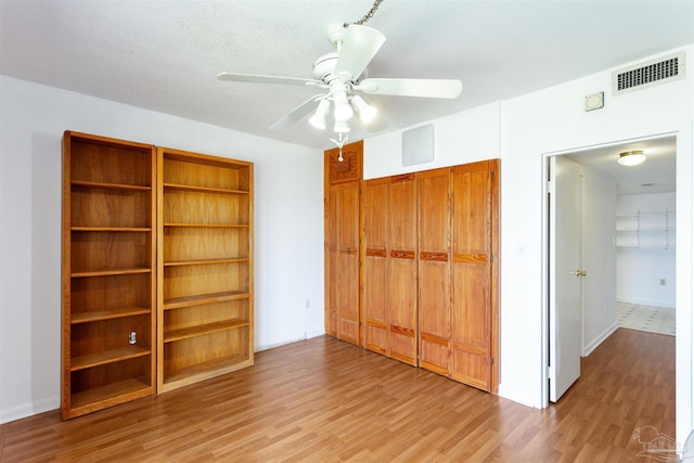 unfurnished bedroom featuring light wood-style flooring, a closet, visible vents, and a ceiling fan