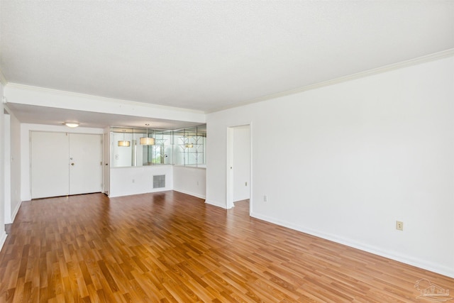 unfurnished living room with ornamental molding, a textured ceiling, and hardwood / wood-style flooring