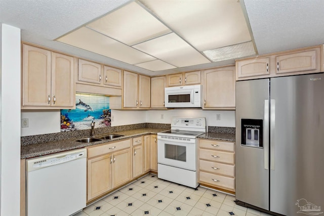 kitchen featuring white appliances, light brown cabinets, a sink, and a textured ceiling