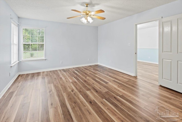 empty room featuring a textured ceiling, light wood-type flooring, and ceiling fan