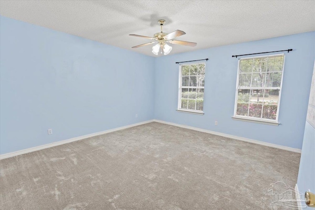 empty room with a wealth of natural light, ceiling fan, light carpet, and a textured ceiling