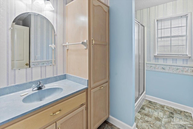 bathroom with a textured ceiling, vanity, and an enclosed shower