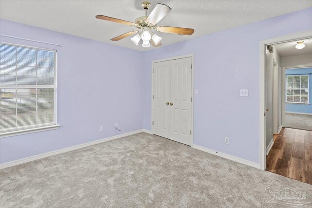 unfurnished bedroom featuring a textured ceiling, ceiling fan, light carpet, and multiple windows