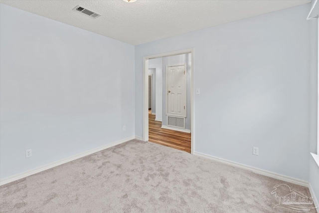 unfurnished room with a textured ceiling and light carpet