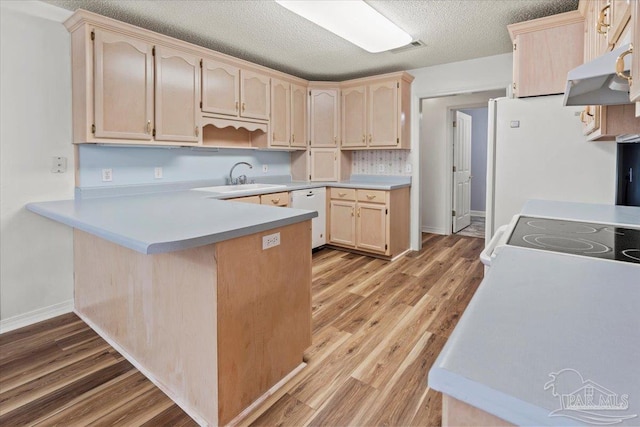 kitchen with white dishwasher, sink, light wood-type flooring, a textured ceiling, and kitchen peninsula