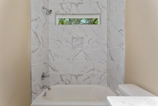 bathroom with tiled shower / bath combo and toilet