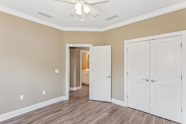 unfurnished bedroom with a closet, crown molding, light wood-type flooring, and ceiling fan