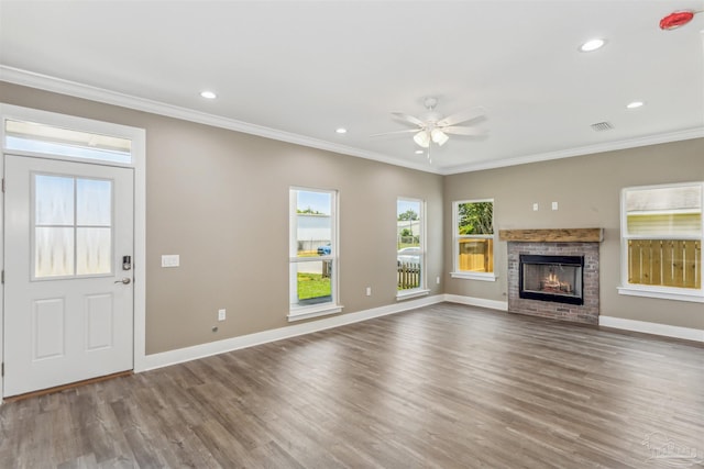 unfurnished living room featuring a fireplace, wood-type flooring, crown molding, and ceiling fan