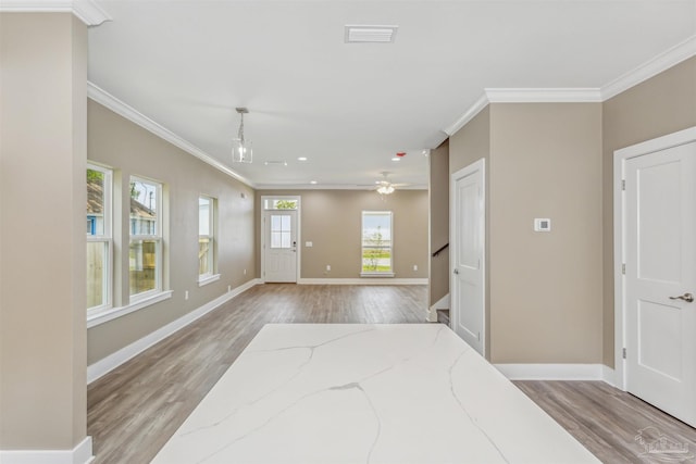 interior space with light wood-type flooring, ceiling fan, and ornamental molding