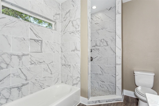 bathroom featuring tiled shower, toilet, a wealth of natural light, and hardwood / wood-style floors