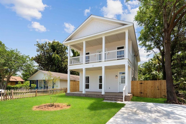 neoclassical home featuring a balcony and a front lawn