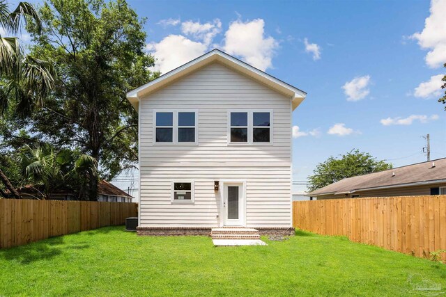 rear view of house with central AC and a lawn