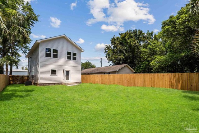 rear view of house featuring central AC and a lawn