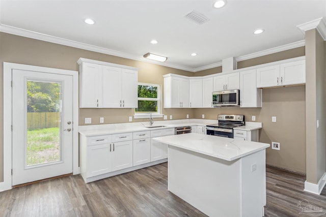 kitchen featuring appliances with stainless steel finishes, wood-type flooring, ornamental molding, and white cabinetry