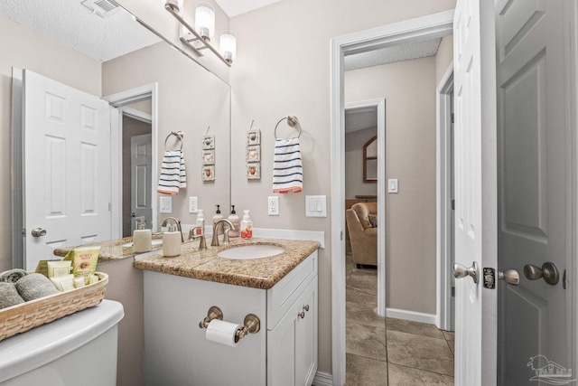 bathroom featuring tile patterned floors, vanity, toilet, and a textured ceiling