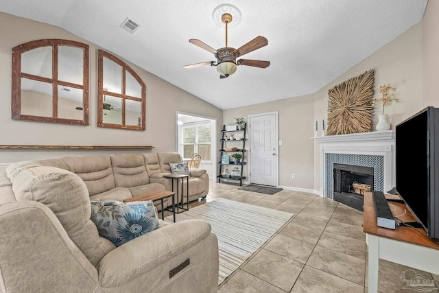 tiled living room featuring a tiled fireplace, lofted ceiling, a textured ceiling, and ceiling fan