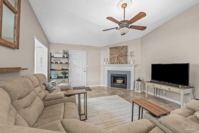 living room with a tile fireplace, lofted ceiling, light tile patterned flooring, and ceiling fan