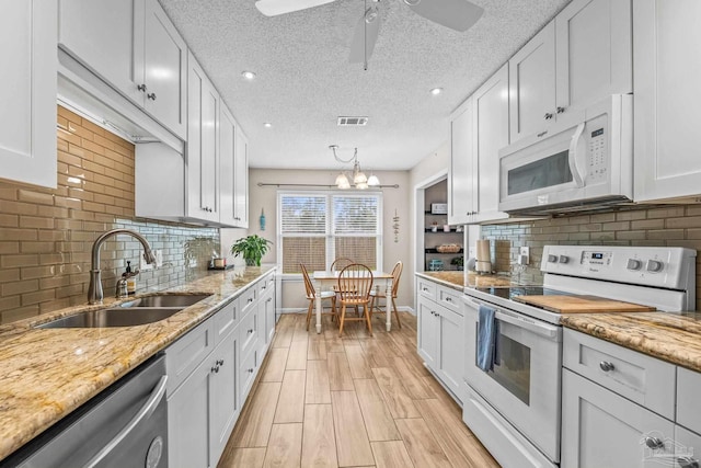 kitchen featuring white appliances, light stone countertops, sink, and white cabinets