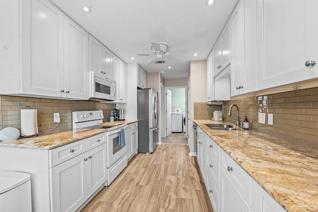 kitchen featuring sink, white appliances, washer and clothes dryer, and white cabinets