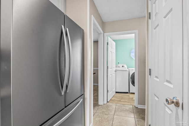 kitchen with light tile patterned flooring, washer / dryer, stainless steel fridge, and a textured ceiling