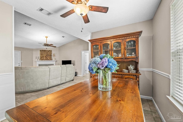 dining area featuring light tile patterned floors, a textured ceiling, vaulted ceiling, and ceiling fan